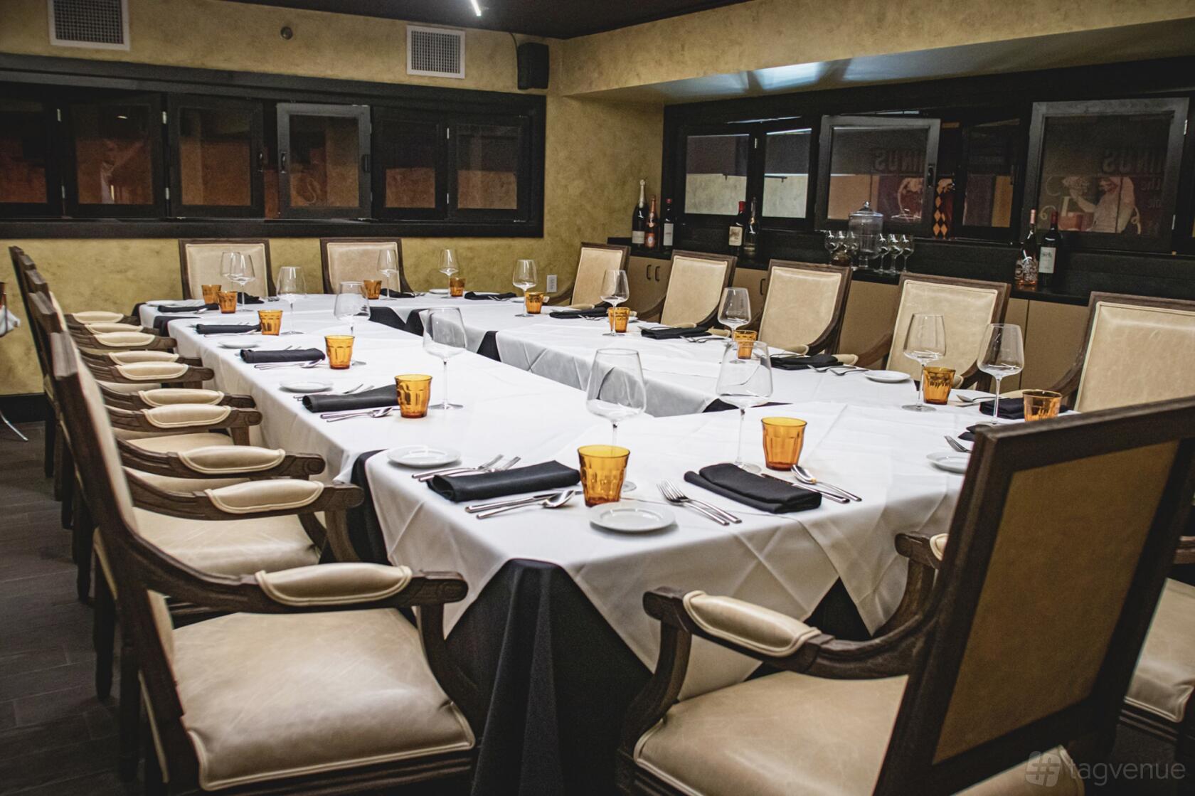 A restaurant dining room with long tables set with glassware, amber water glasses, and upholstered chairs at Brasserie Du Parc.
