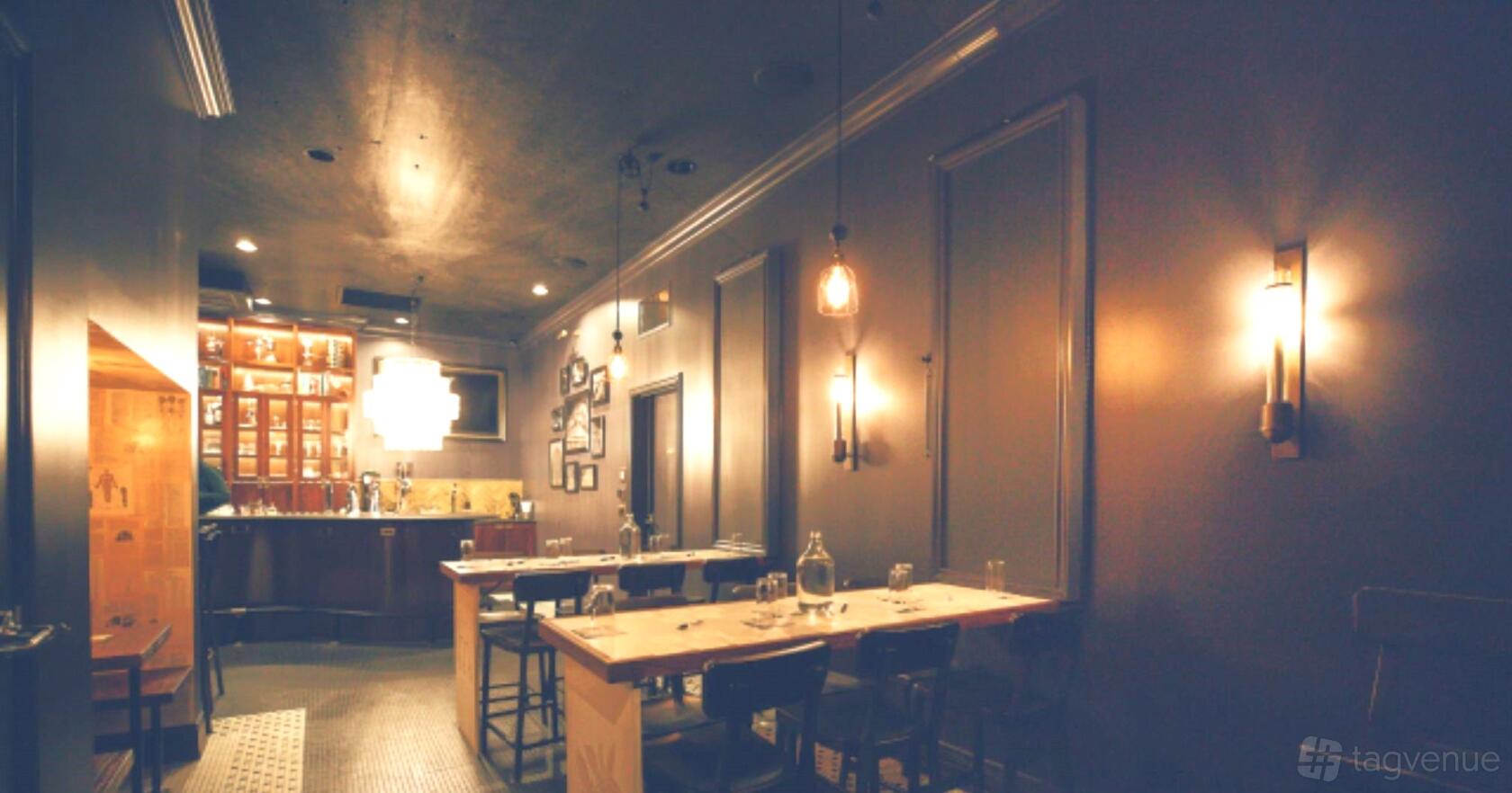 An event venue with pendant lighting, framed wall panels, and wooden tables set with glassware at The Lab at Ada's.