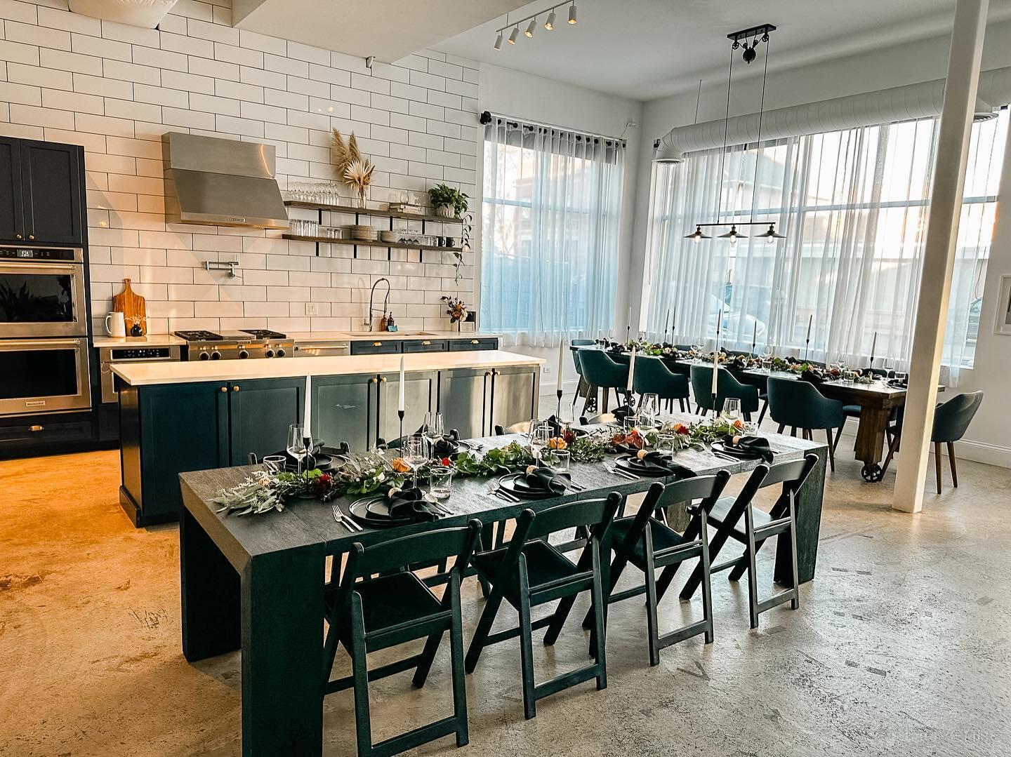 A function room with a demonstration kitchen, large windows, and banquet tables set for dining at RLM Events and Design.
