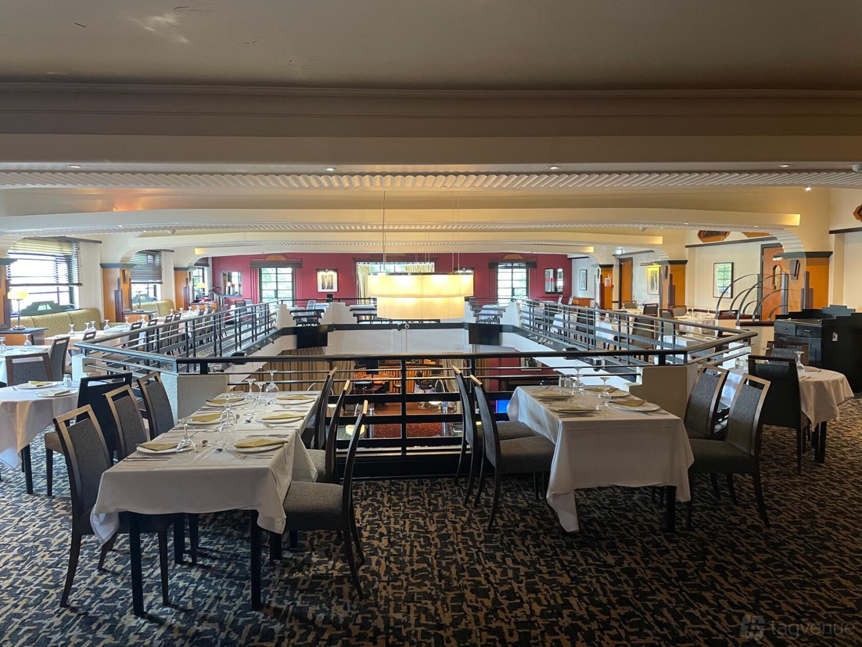 An event venue with white-clothed tables, set for dining, overlooking a mezzanine at The Maybury Casino.