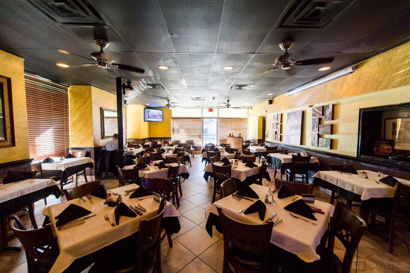A restaurant with tile flooring, yellow walls, ceiling fans, and tables set with white linens at Vila Brazil.