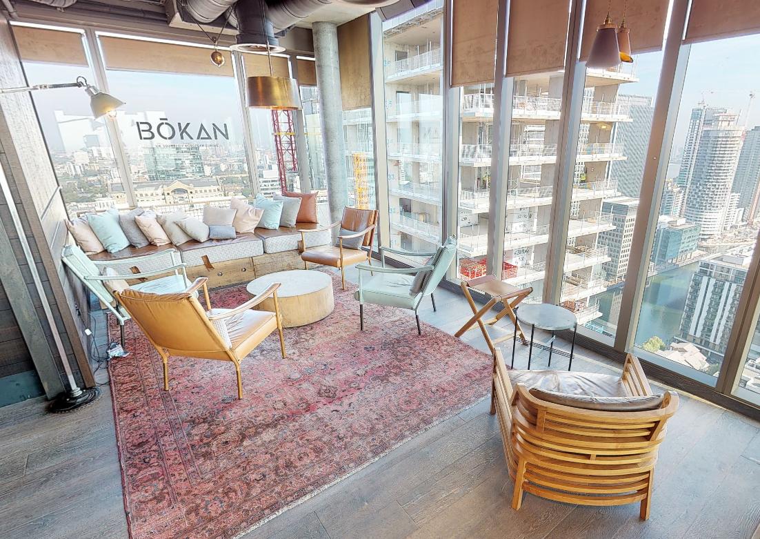 A rooftop event space with floor-to-ceiling windows, city views, and lounge seating at Bōkan 39 Roof Terrace Bar.