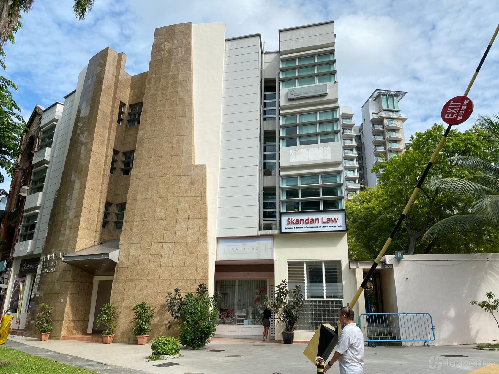 A multi-storey building exterior with beige stone panels and potted plants at the entrance of Danspirations Studio 2.