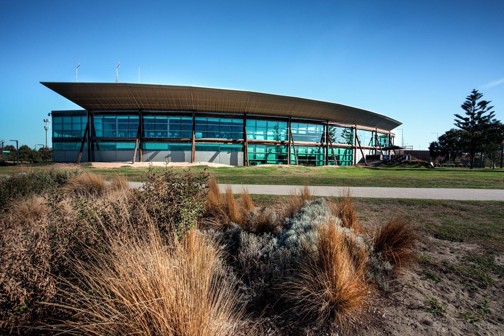 A meeting centre with curved roof, large glass windows, and landscaped native plants at The Views LSV.