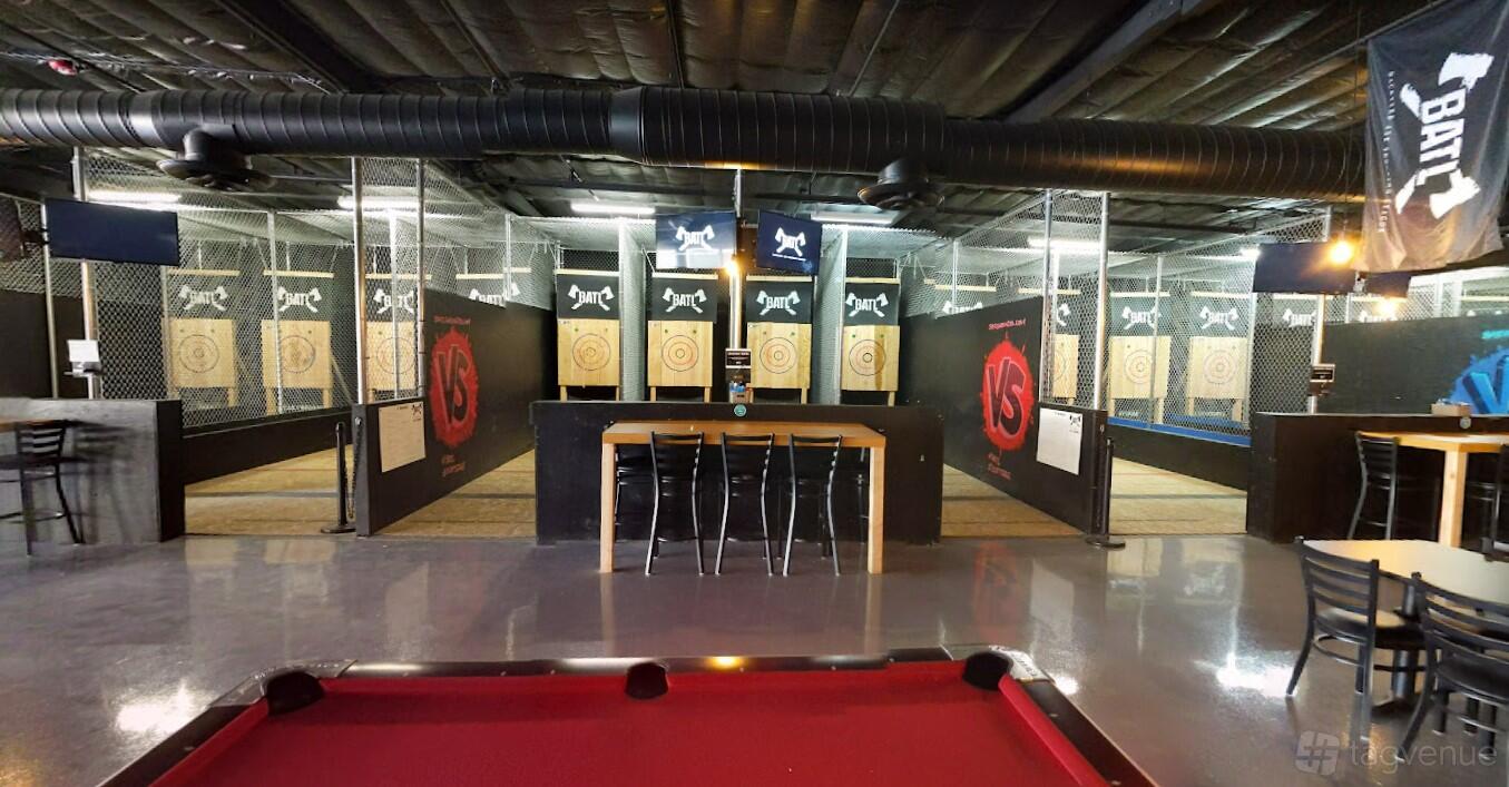 A sports club with axe throwing lanes, wooden targets, and a pool table at BATL Grounds Scottsdale.