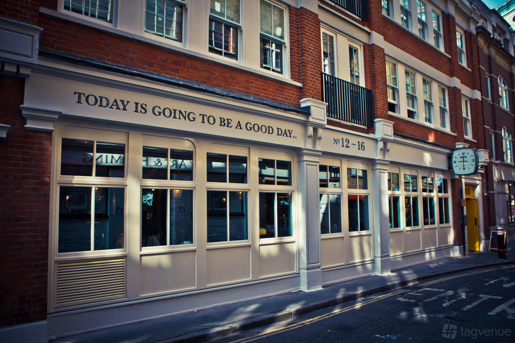 A pub with cream-framed windows, red brick exterior, and a sign reading 'Today is going to be a good day' at The Breakfast Club Spitalfields.