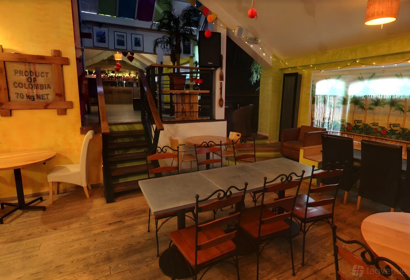 An event space in a restaurant with wooden floors, iron chairs around a long table, and string lights at Casa Leeds.
