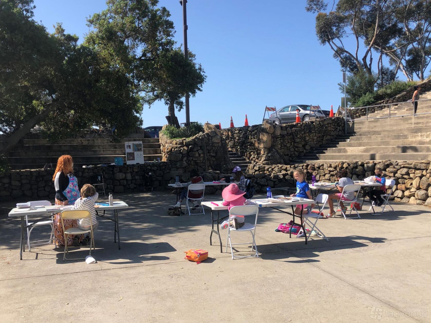 An outdoor event venue with stone terraced seating and scattered tables under trees at Mt. Helix Park.