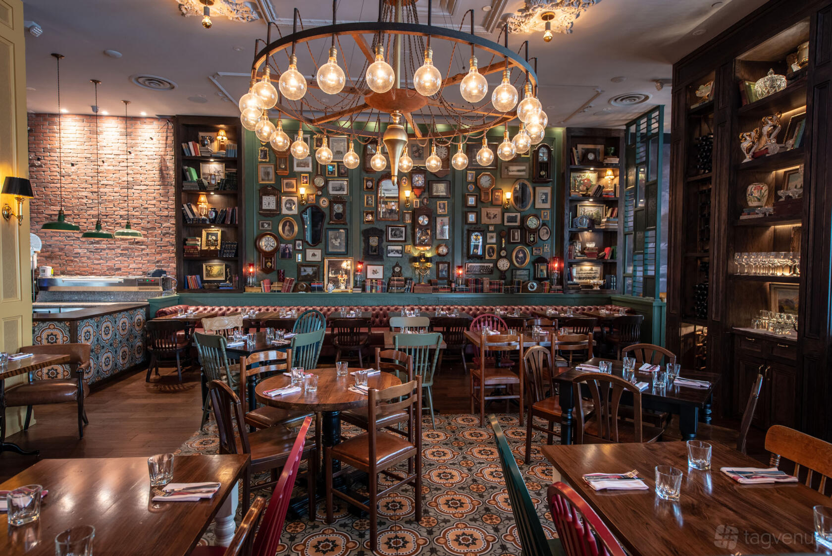 A dining room with an eclectic mix of wooden chairs, patterned tile floors, and a chandelier at The Good Son Don Mills.