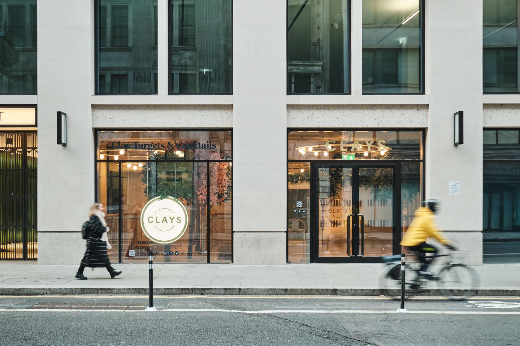 A pub with large glass windows and exterior signage on a city street at Clays City.