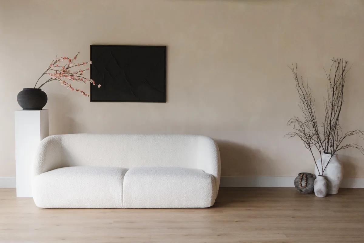 A photo studio with a white boucle sofa, neutral walls, wooden floors, and minimal decor at Sahara Loft.
