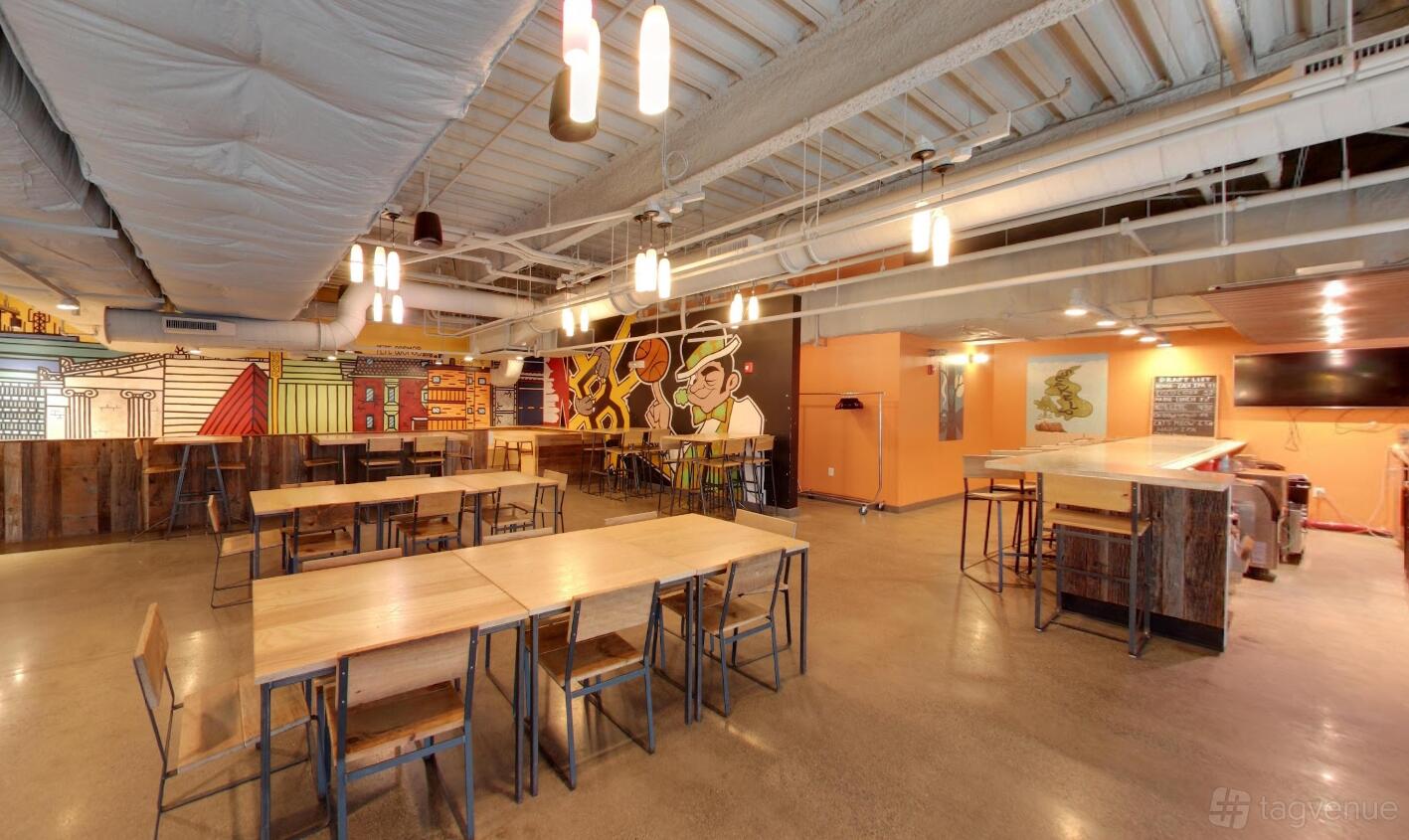An event space in a bar with wooden tables, industrial lighting, exposed ceiling, and vibrant murals at Brighton Bowl.