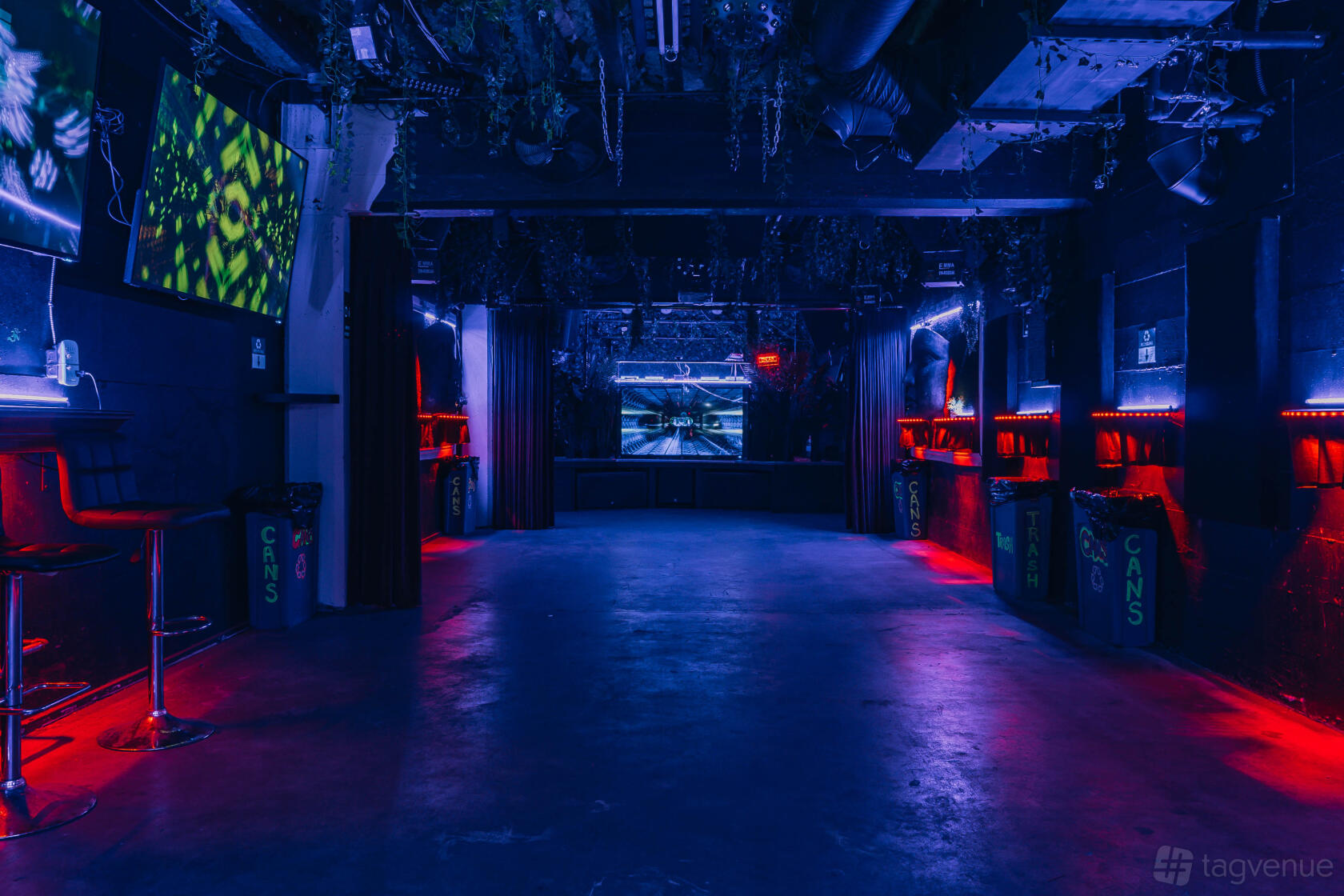 A nightclub with neon lighting, bar seating along the walls, and multiple large digital screens at Private Event Rental Space.