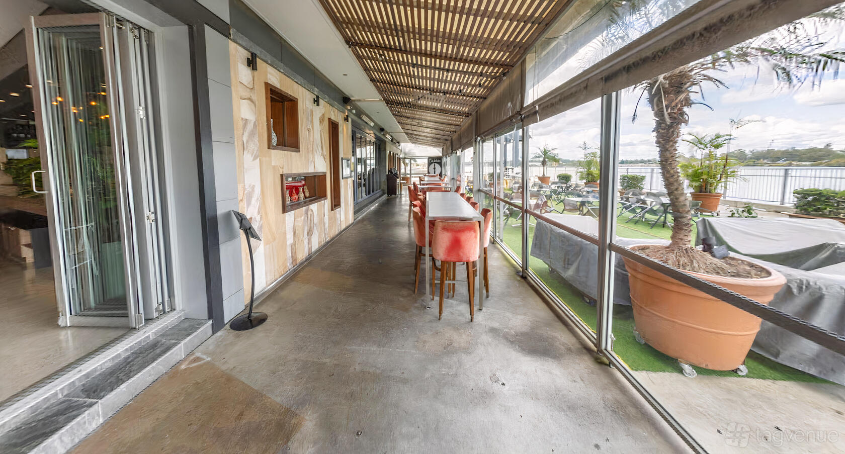 A restaurant dining room with long tables, pink velvet chairs, and floor-to-ceiling windows at Gusto da Gianni.