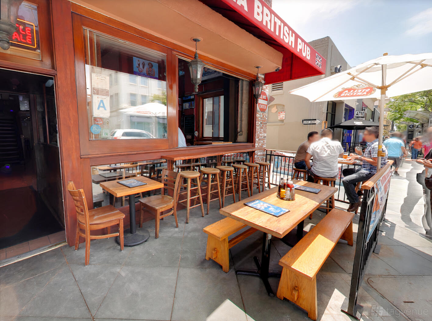 An outdoor pub patio with wooden tables, chairs, and large umbrellas at Britannia Pub.