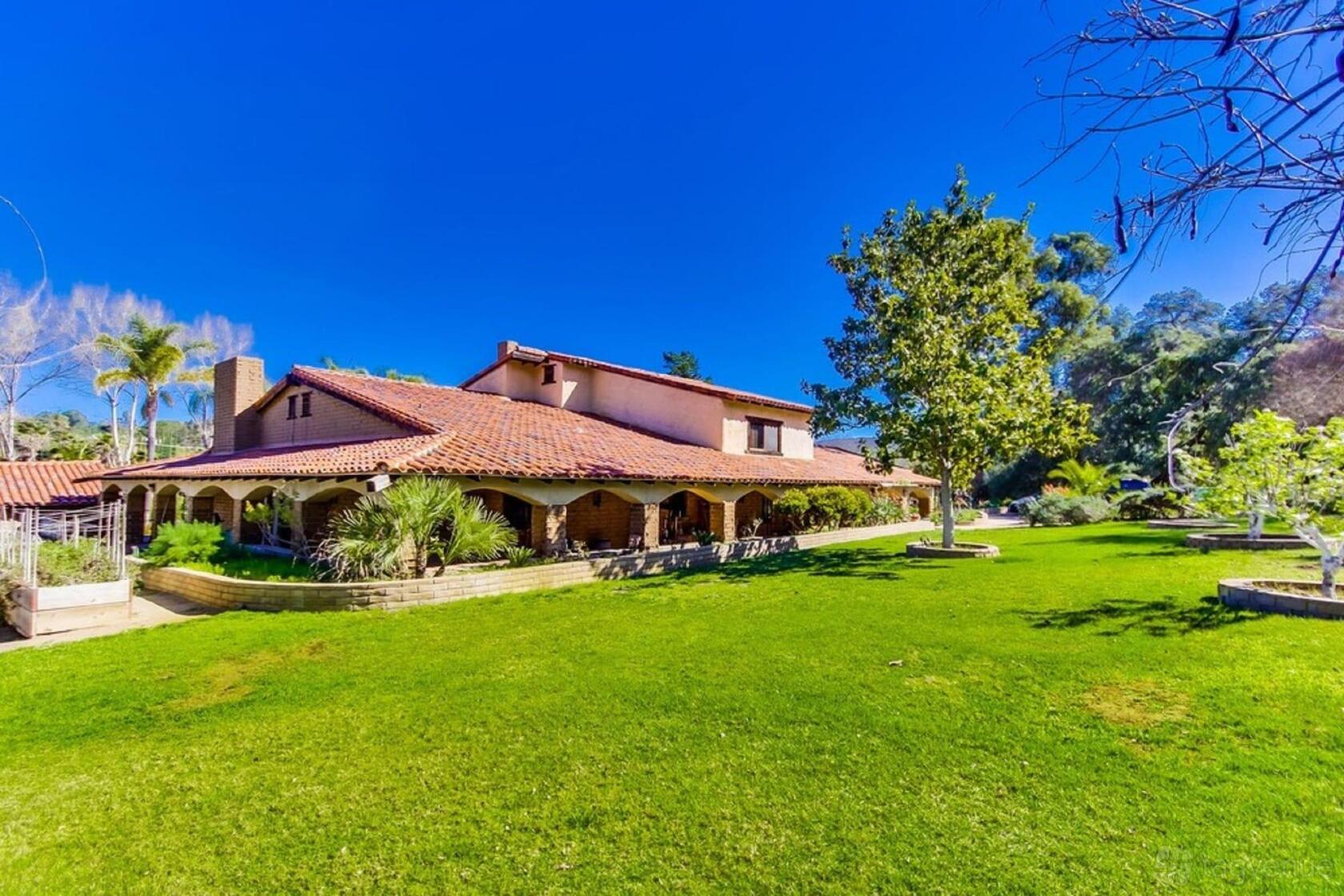 A versatile event space with a red-tiled roof, shaded wraparound porch, and large lawn at Vineyard Hacienda.