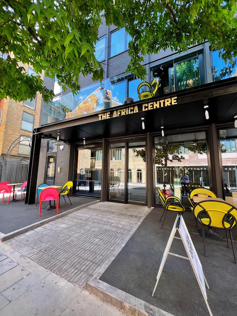 An event space with colorful outdoor seating and glass doors beneath the sign at The Africa Centre.