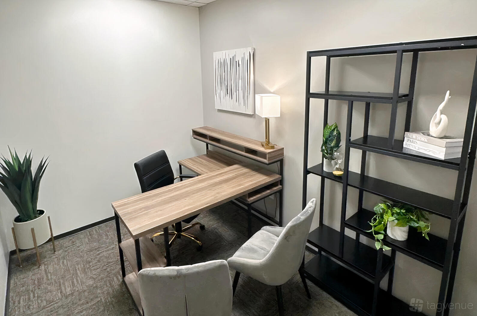 An office space with a wooden desk, modern chairs, open shelving, and potted plants at Lucid Private Offices - Sugar Land.