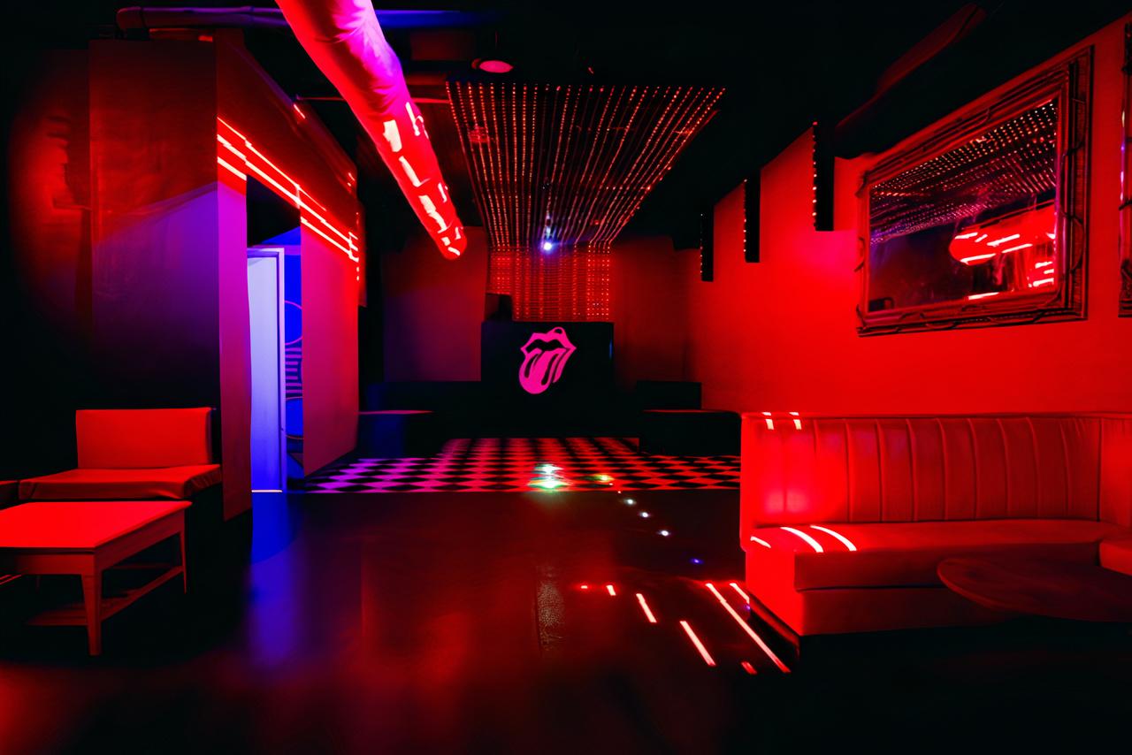 An event space in a nightclub with red LED lighting, checkered dance floor, and booth seating at Dakota Nightclub.
