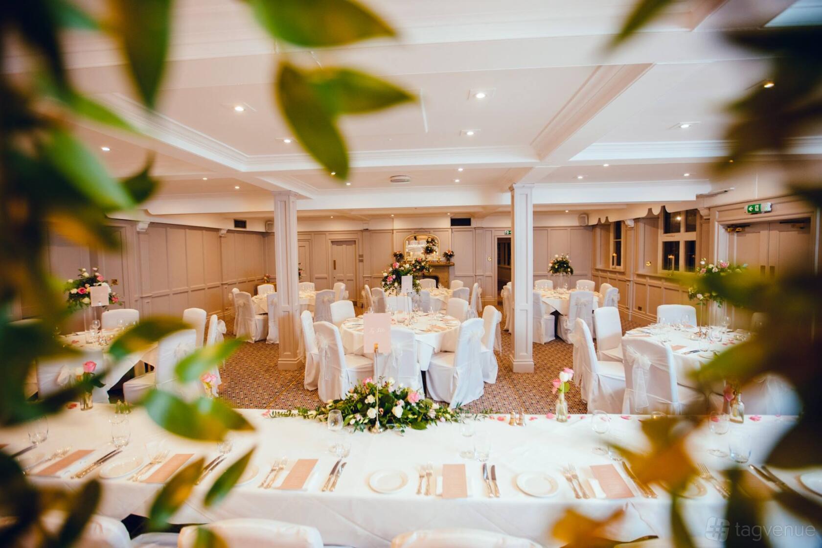 A hotel event room with round tables dressed in white linens and floral centerpieces at Devonshire Arms Hotel & Spa.