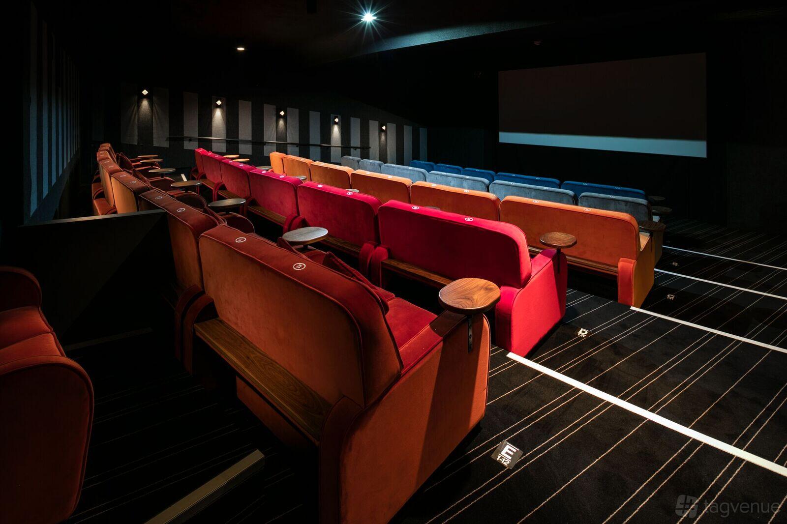 A cinema screening room with plush red and blue seating, tiered rows, and a large projection screen at Everyman York.