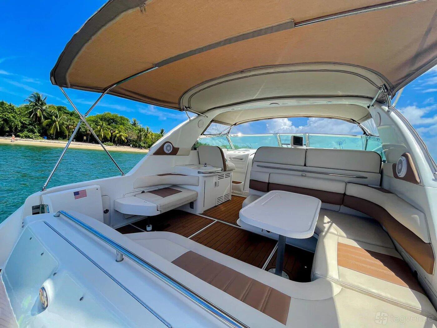 A yacht deck with cushioned seating, a white table, and shaded canopy at VIP Boat Rental @ Alton Road.