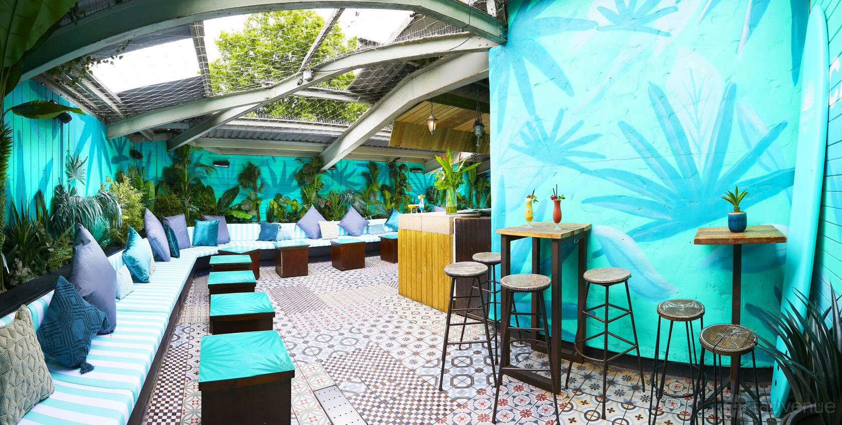 An event space in a nightclub with mosaic tile flooring, turquoise walls, and built-in bench seating at Embargo Republica.