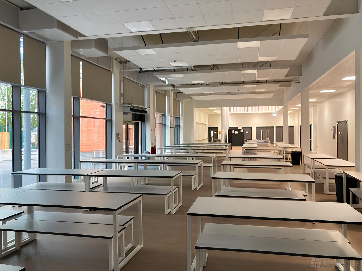 A school hall with rows of long white tables, large windows, and roller blinds at BOA Digital School Academy.