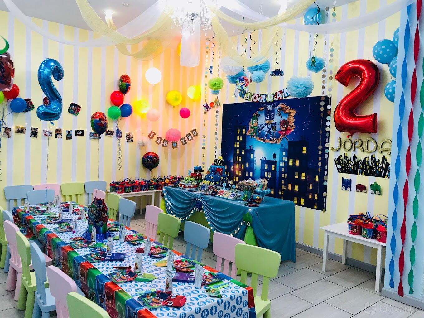 An event venue decorated for a children's party with themed tablecloths, colorful balloons, and wall streamers at Fairytale Island.