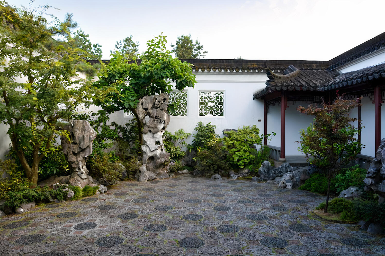 An outdoor courtyard with patterned stone flooring, ornamental rocks, and traditional Chinese garden walls at Dr. Sun Yat-Sen Classical Chinese Garden.