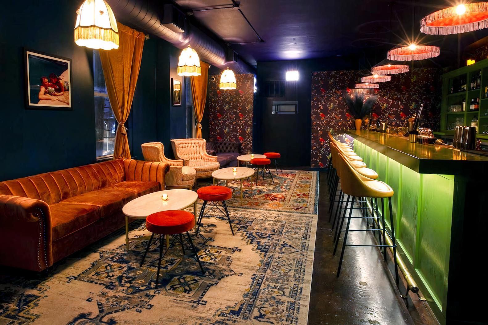 A function room in a pub with velvet sofas, marble tables, patterned rugs, and a green-lit bar at The Albion Manor.