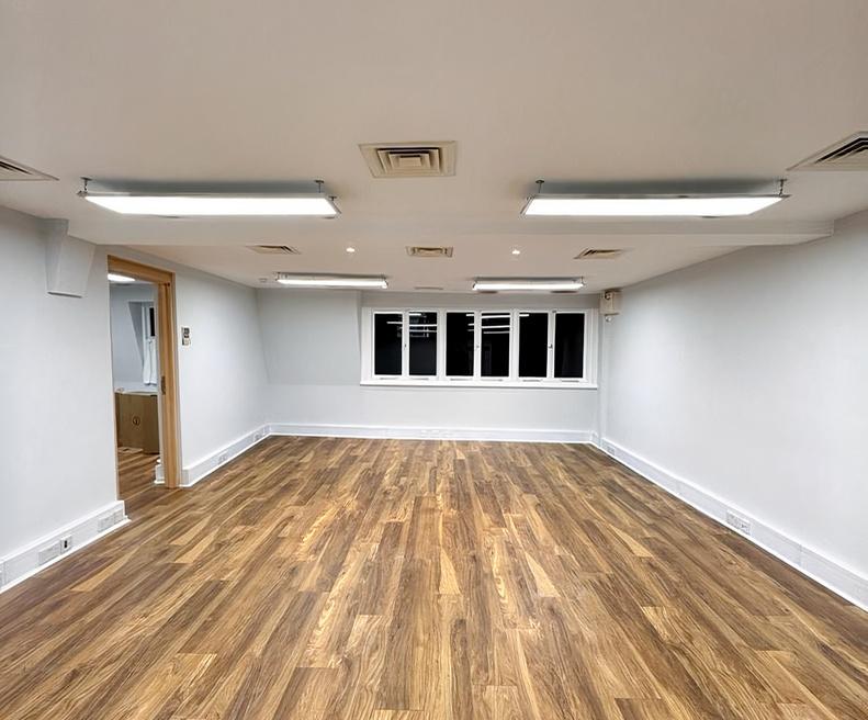An event venue with wood flooring, white walls, and bright overhead lighting at Widegate E1.