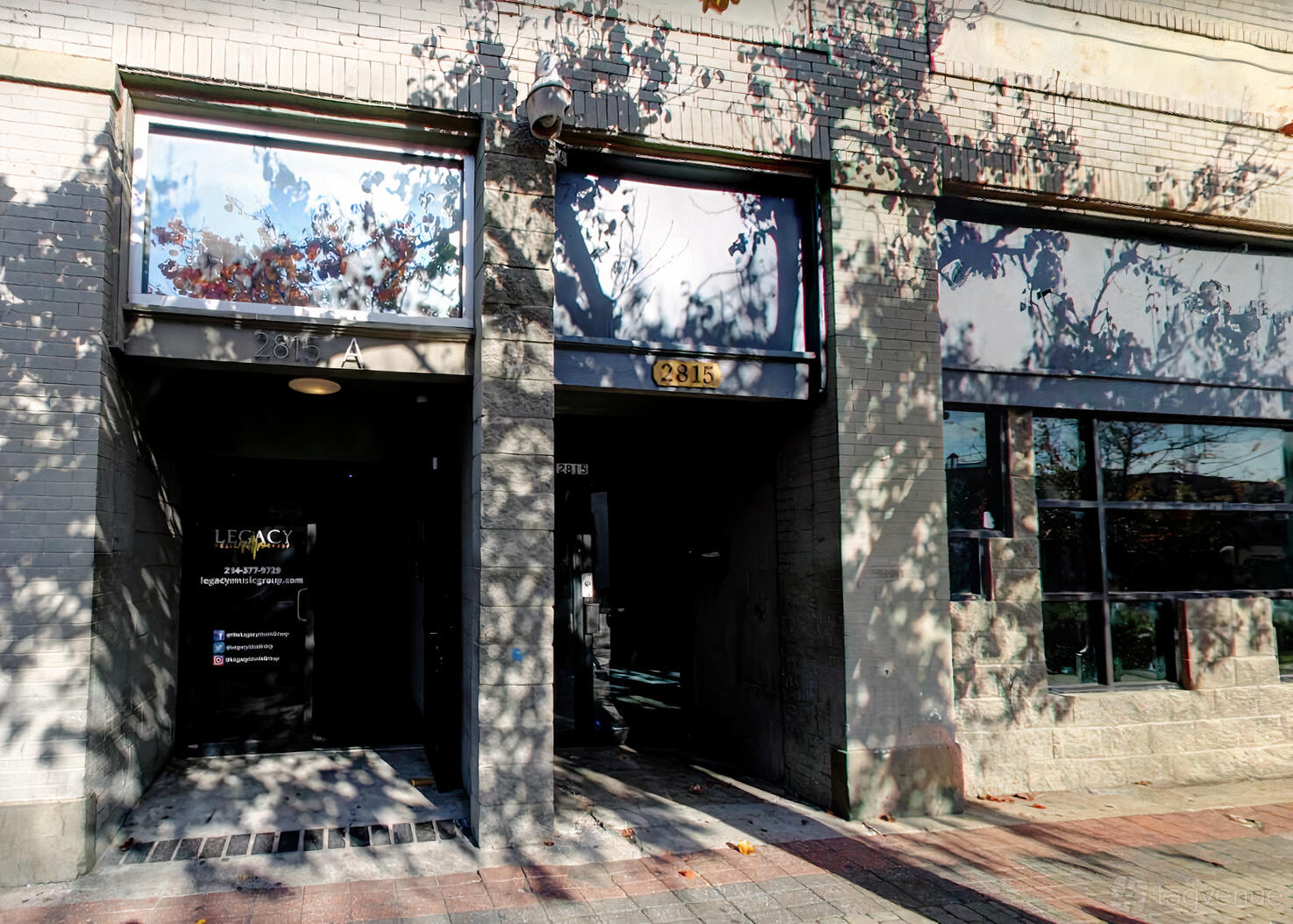 A recording studio exterior with large front windows and a shaded entrance at Legacy Music Group.