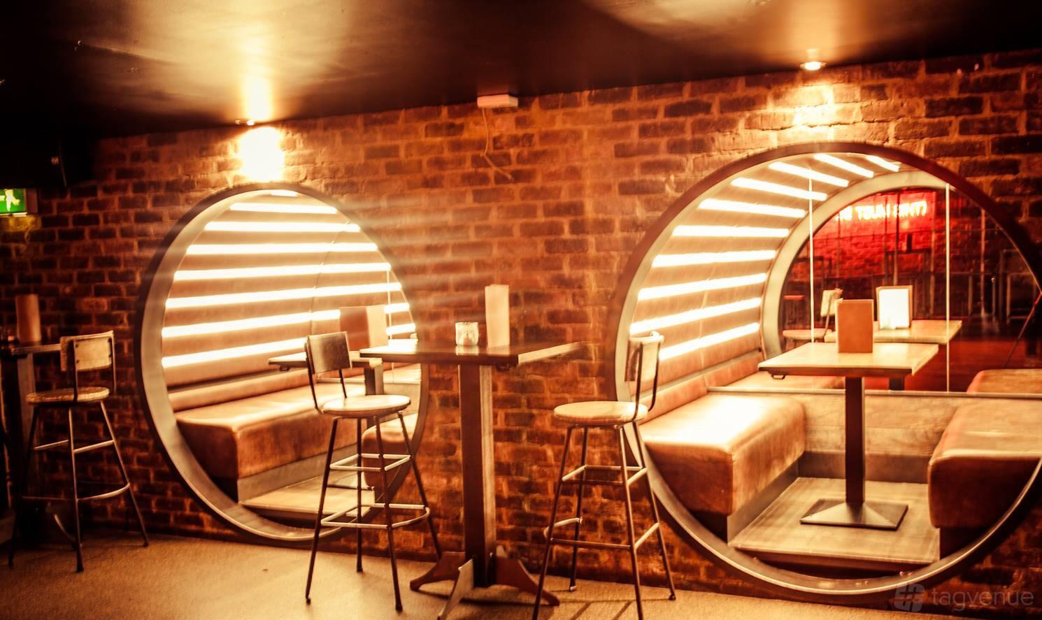 A bar with circular booth seating set into exposed brick walls and warm ambient lighting at Core.
