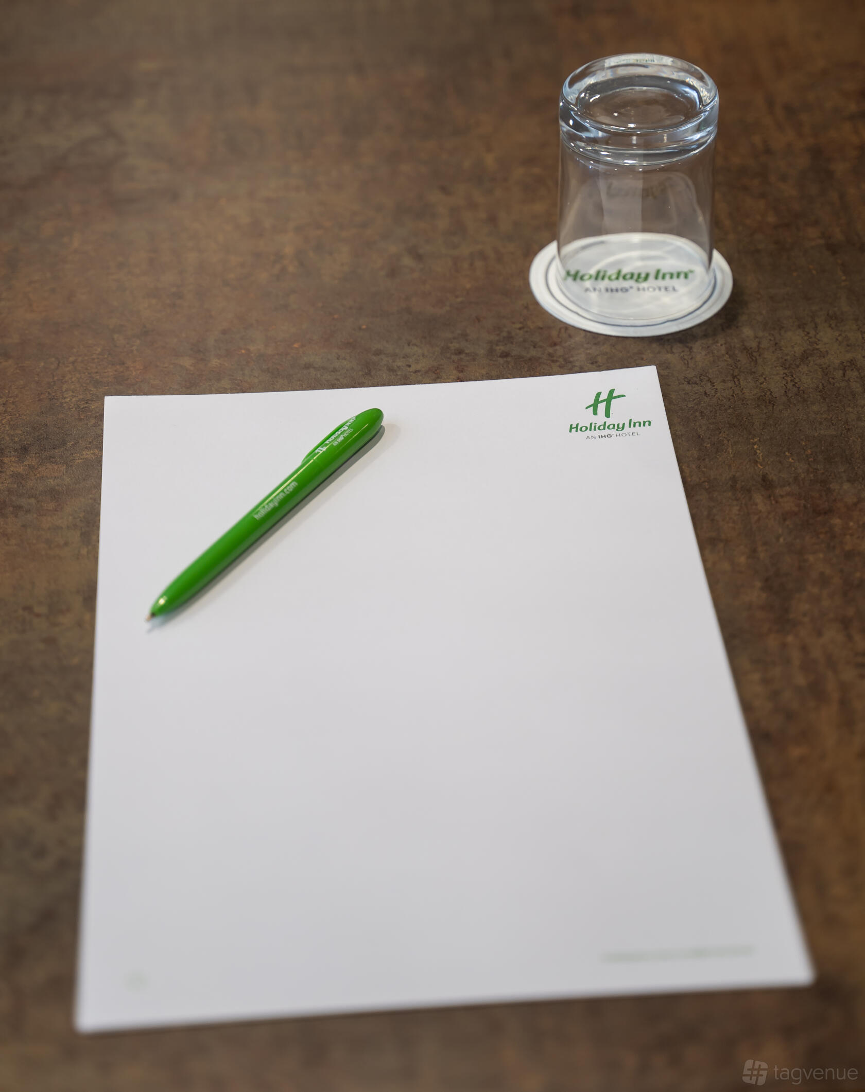 A green pen and branded notepad placed on a meeting table at Holiday Inn Leicester - Wigston.