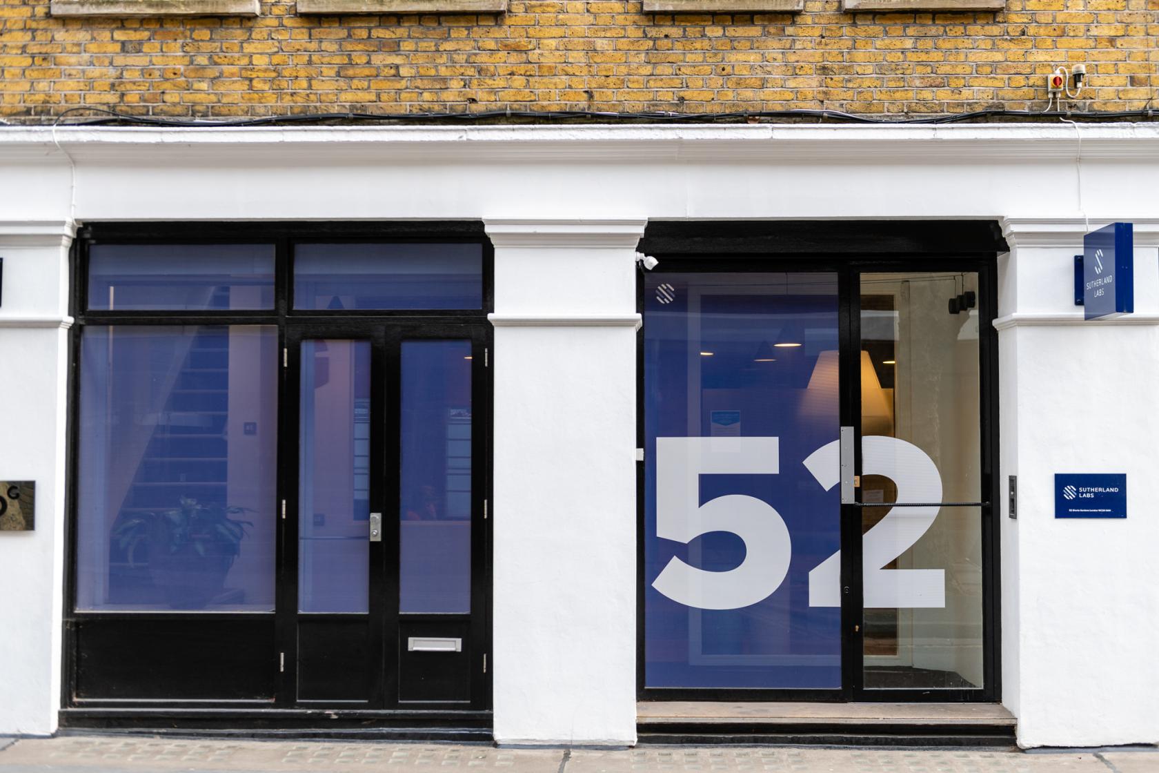 A meeting centre with a glass entrance, large '52' window decal, and exposed brick façade at Sutherland Labs.