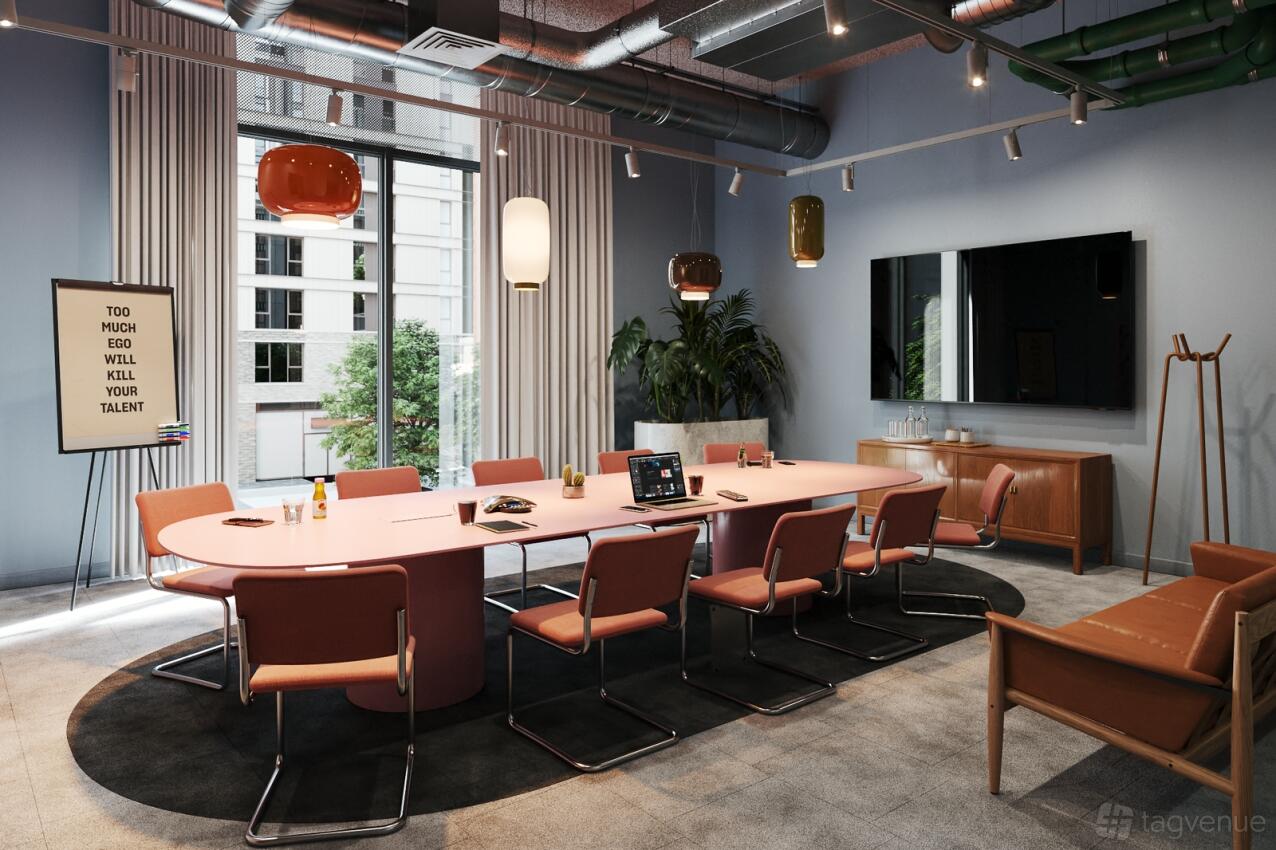 A boardroom with a pink conference table, modern chairs, large window, and pendant lighting at The Social Hub.