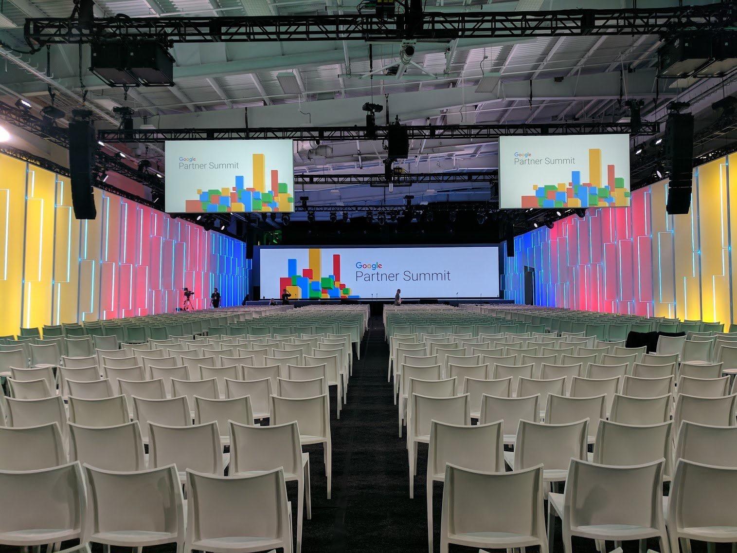 An event venue with rows of white chairs, colorful LED wall panels, and large projection screens at Pier 36 NYC.