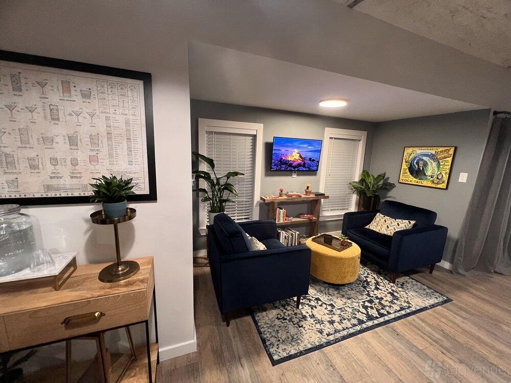 An event venue with navy sofas, a patterned rug, wall art, and a TV lounge area at Cocktail Crafthaus Co.