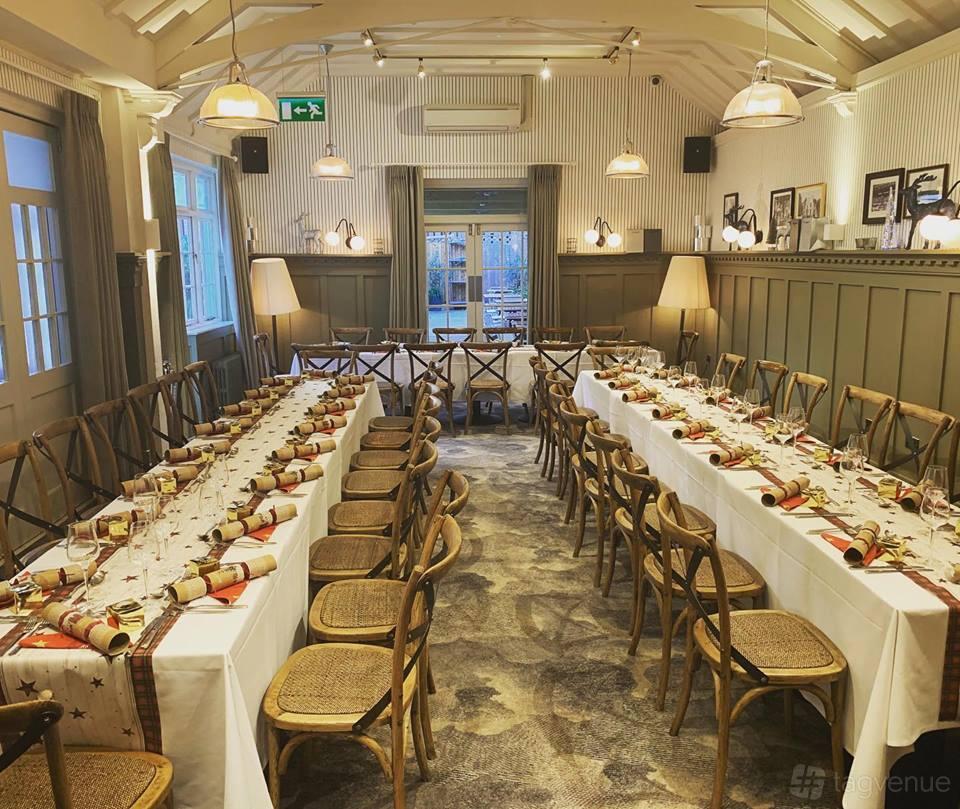 An event space in a hotel with U-shaped banquet tables, wooden chairs, and neutral decor at The Fox and Goose Hotel.