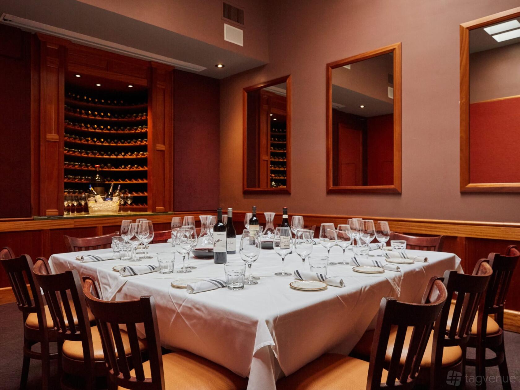 A private dining room with a square table set for twelve and a wall wine display at Vivace.