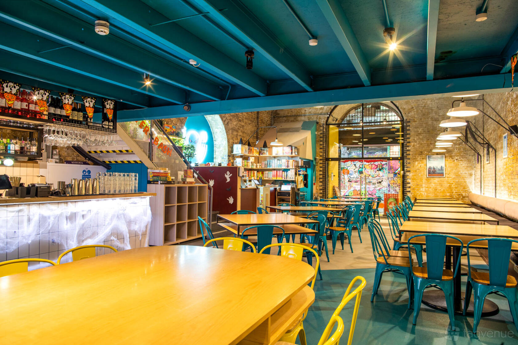 A pub with colorful metal chairs, wooden tables, exposed brick walls, and board games at Draughts Waterloo.