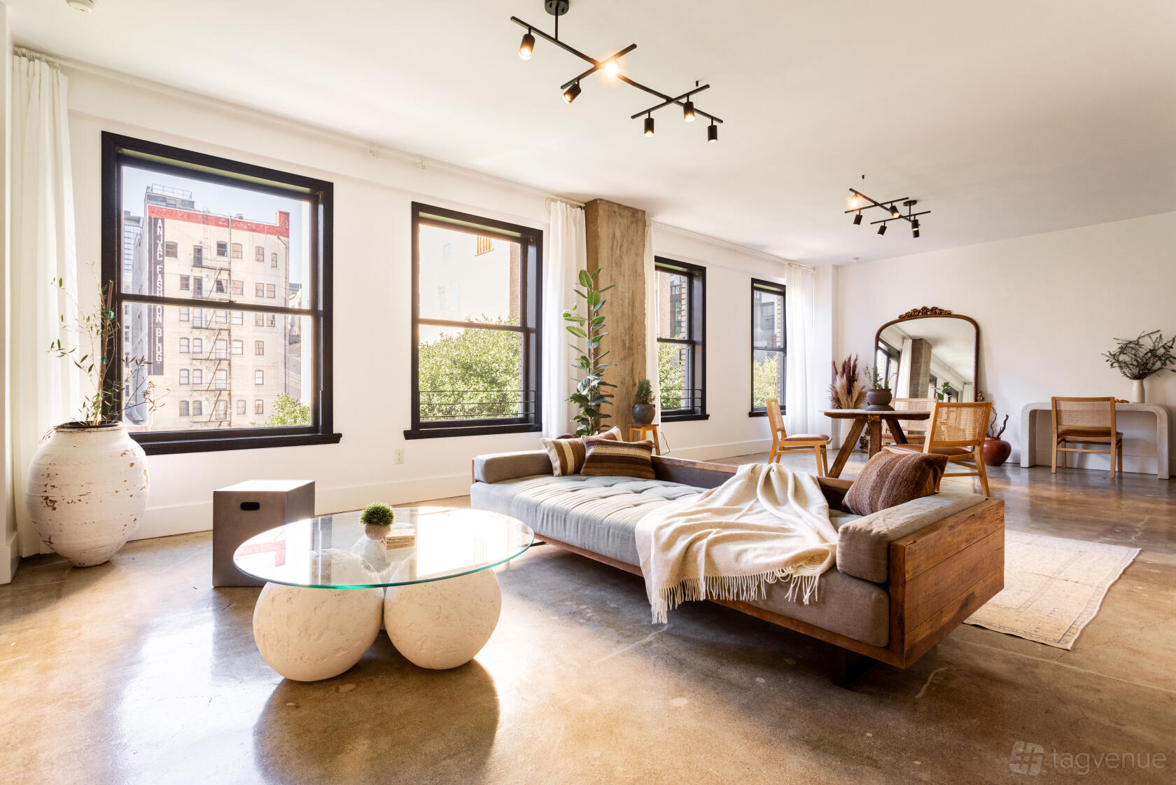 A loft with large windows, polished concrete floors, and modern wooden furniture at Phase 2.