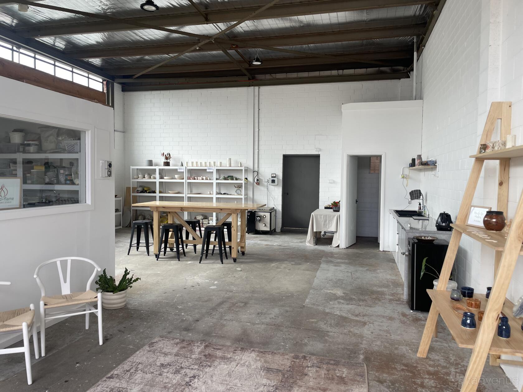 A warehouse with exposed beams, concrete floors, and open shelving at Mud + Flame Studio.