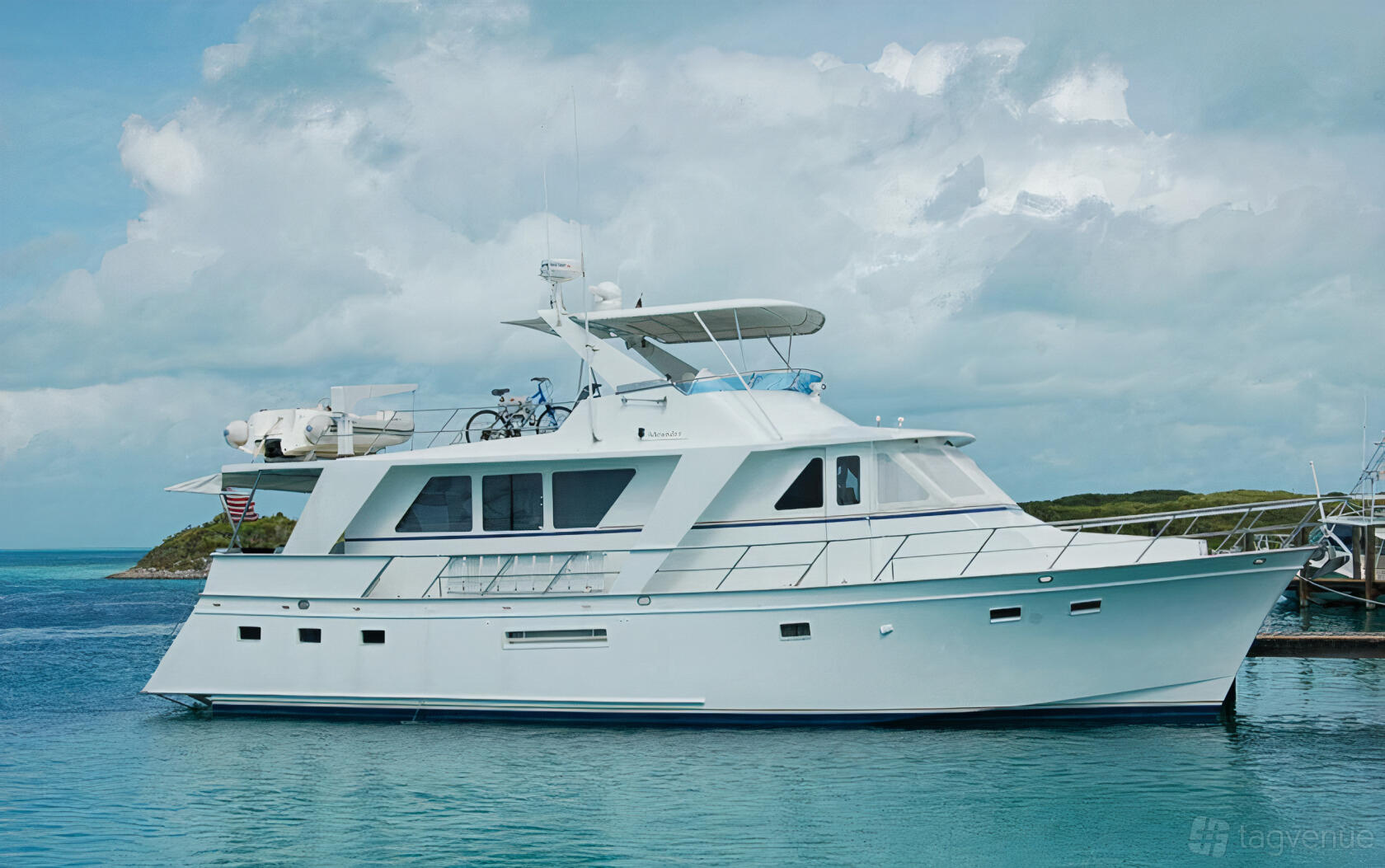 A white yacht with upper deck seating, a covered flybridge, and docked next to clear blue water at Happiest Ours Yacht - Marina Del Rey.
