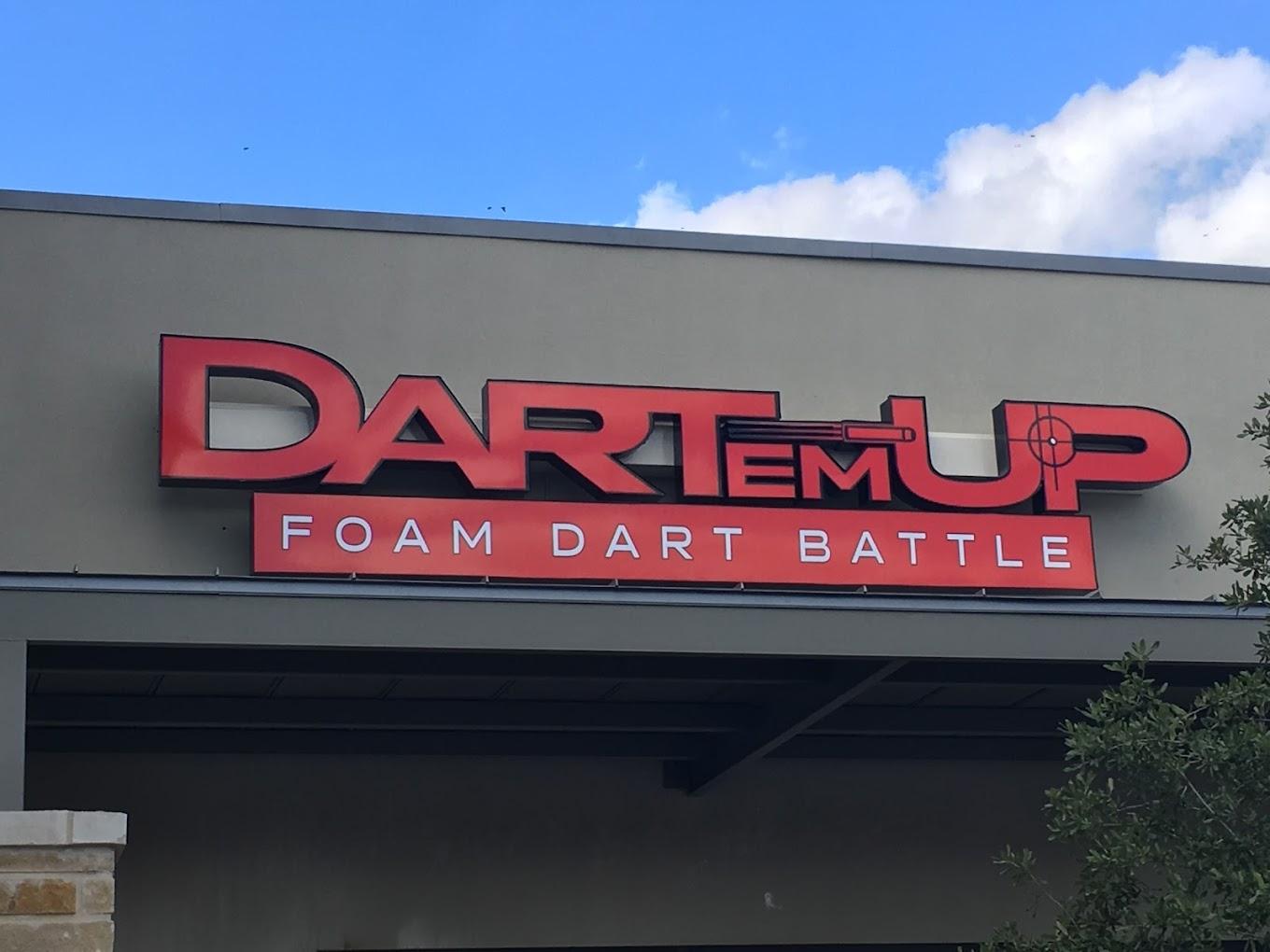 An exterior entry with a large red Dart'em Up sign and partial view of the building facade at Dart'em Up.