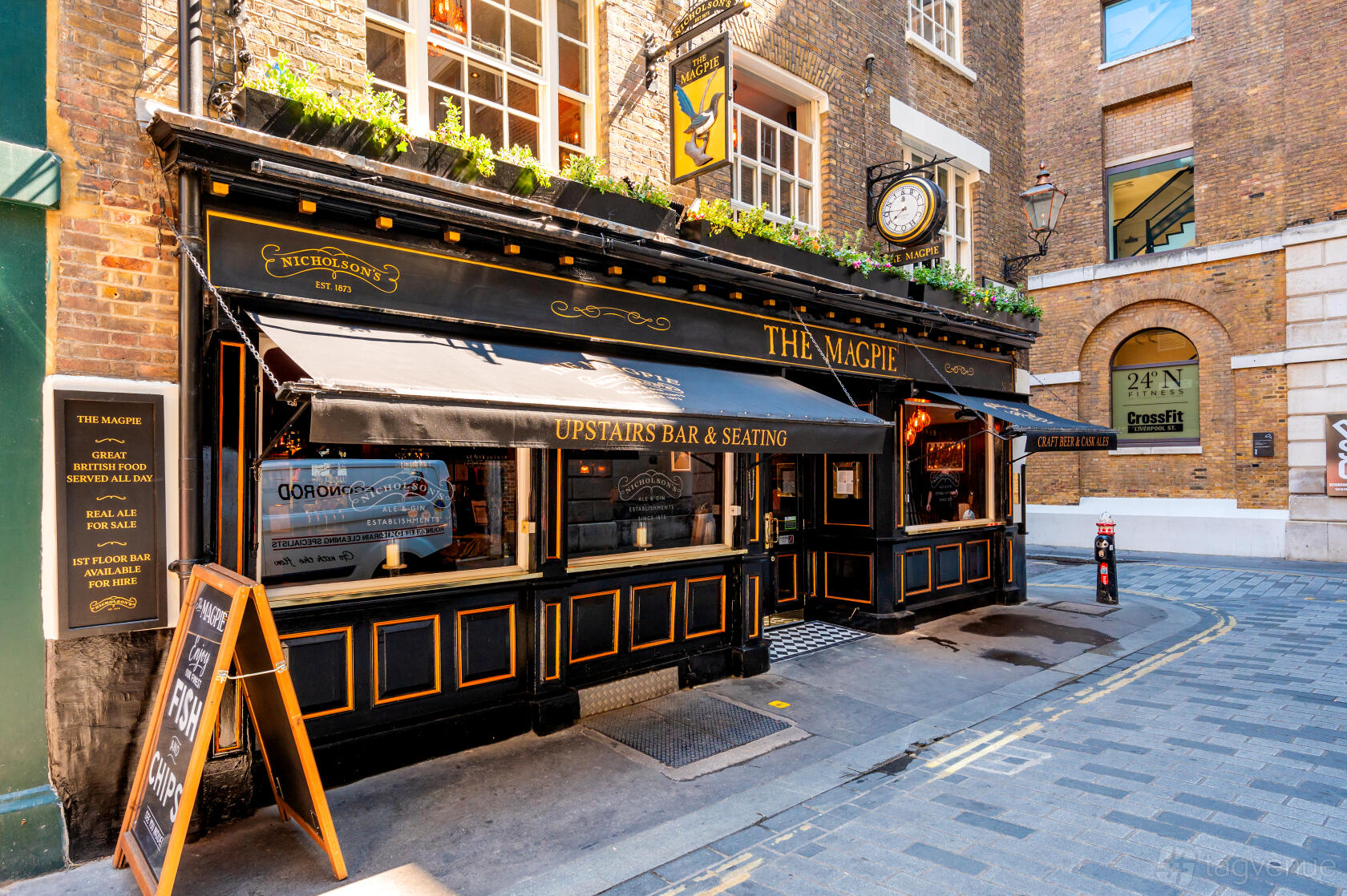 A traditional pub with black and gold exterior, large awnings, and street-facing windows at The Magpie.